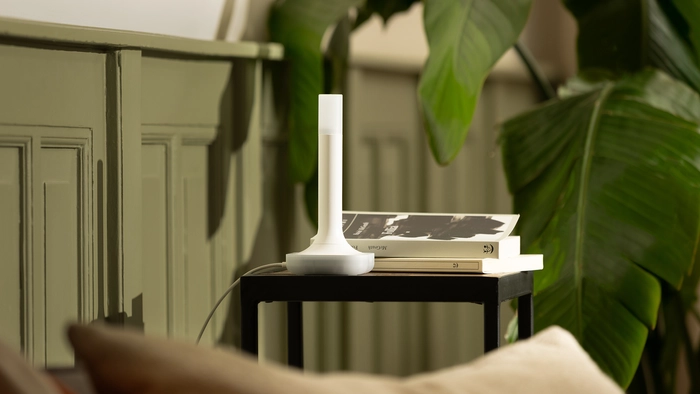 Home Assistant Imprescindible ZBT-2 6 The Home Assistant Connect ZBT-2 device placed next to a stack of books on a black side table, next to a large green houseplant.
